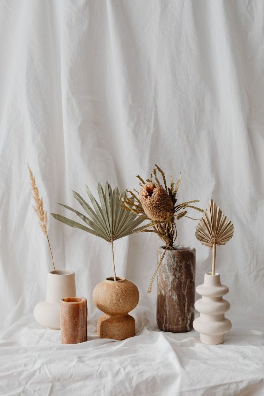 Petits vases avec feuilles séchées sur un tissu blanc