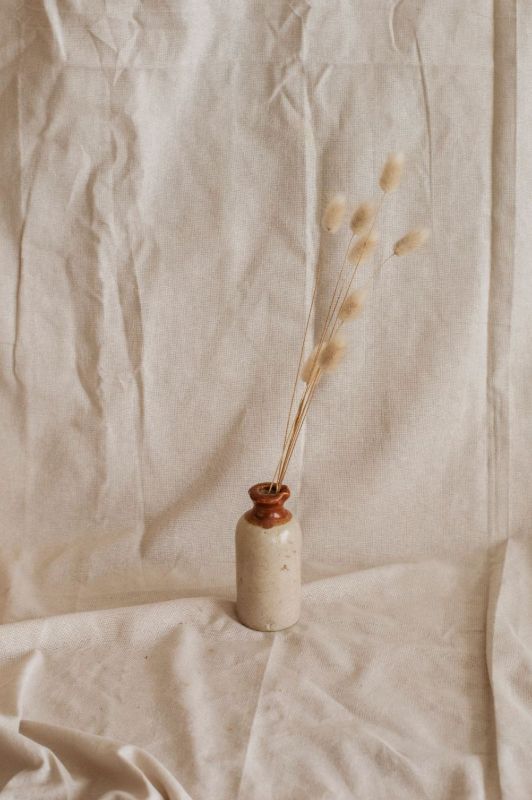Keramikvase mit Trockenblumen auf Leinenstoff