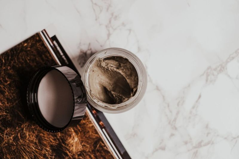 Pot en verre avec un masque à l’argile sur du marbre