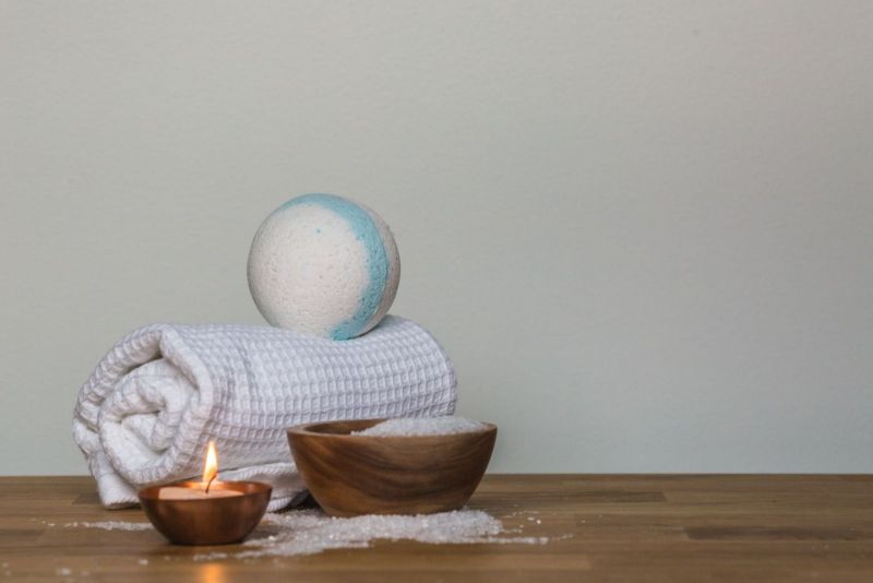Sales de baño, toalla y vela sobre una mesa de madera