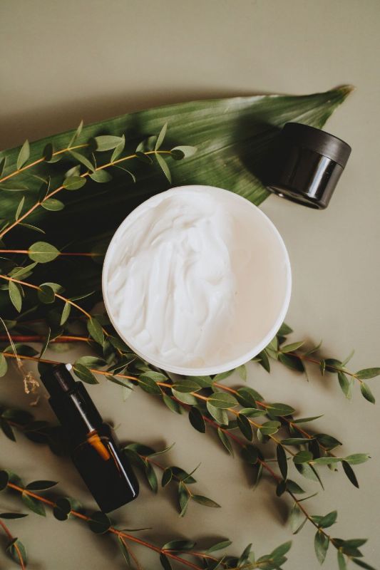 Crema cosmética entre hojas verdes