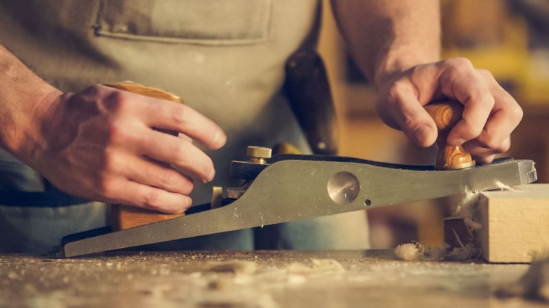 Mains avec un rabot de menuisier sur le bois