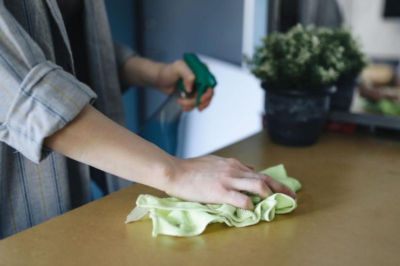 Hände wischen einen Tisch mit einem Tuch ab