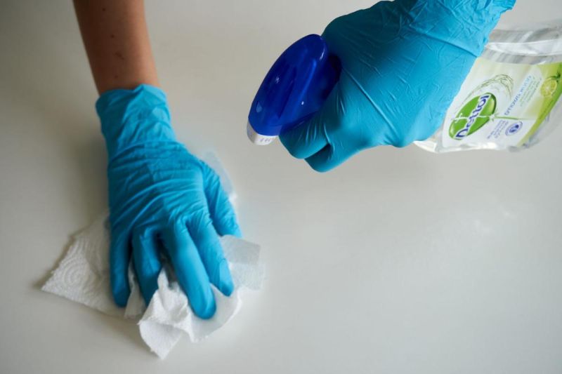 Hand in a blue glove wiping a surface