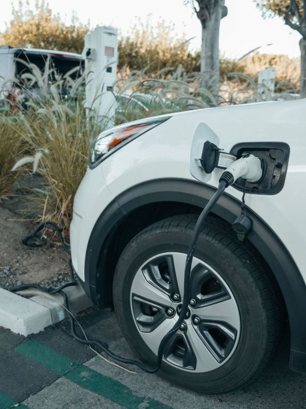 Cable de carga enchufado a un coche eléctrico blanco