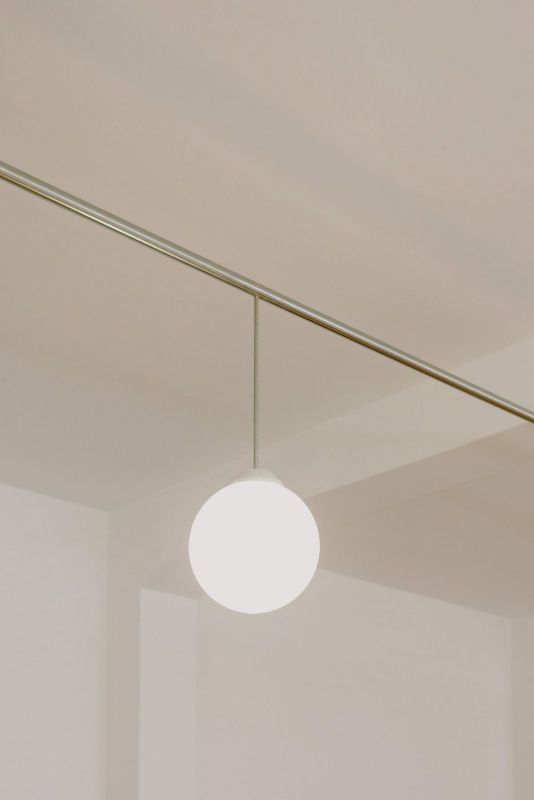 Lámpara esférica colgada de un cable en una habitación luminosa