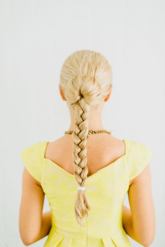 Trenza rubia larga con un vestido amarillo, de espalda