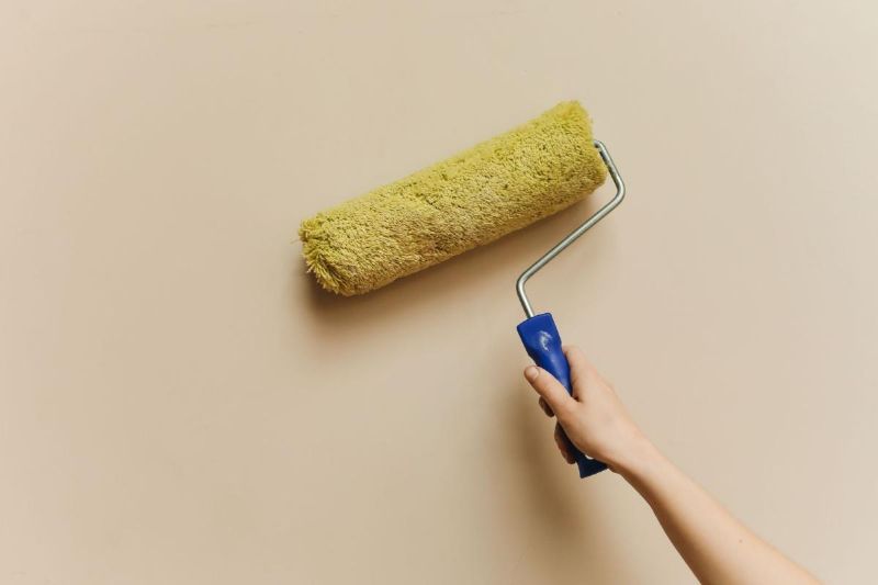 Farbrolle an einer beigen Wand