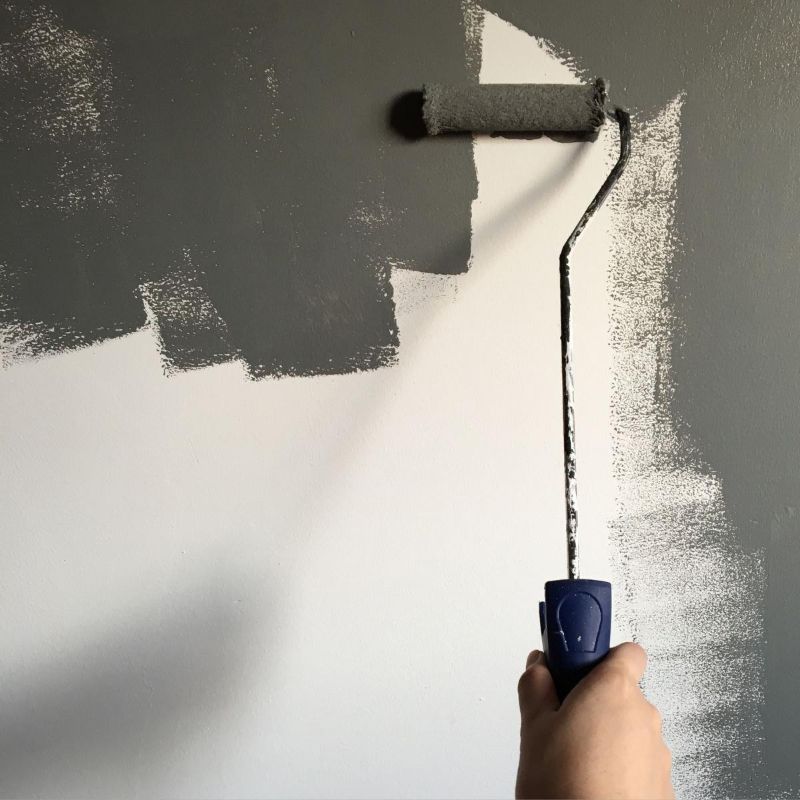 Rodillo pintando una pared de gris oscuro