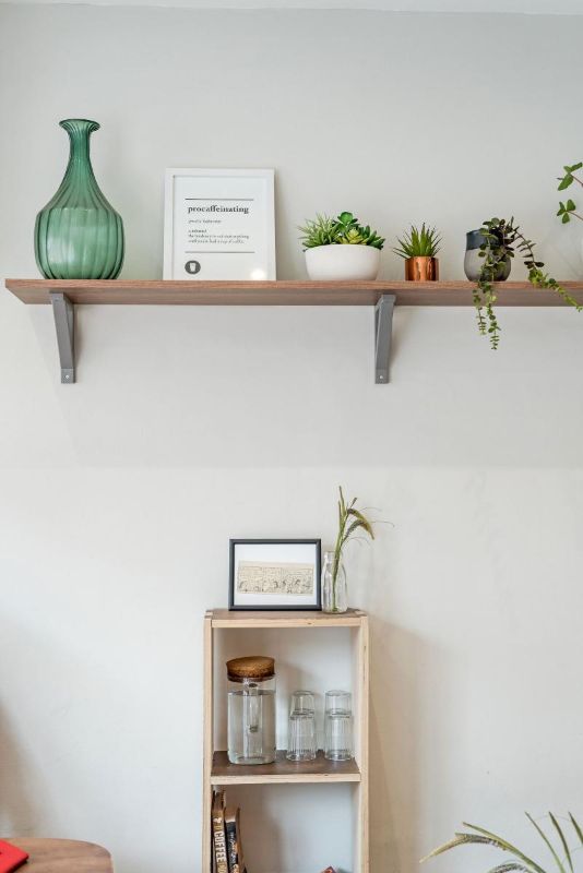 Balda de madera montada en una pared blanca con unas plantas
