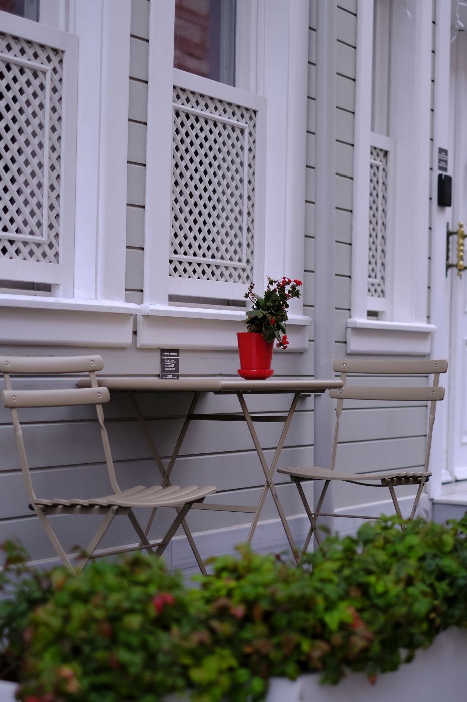 Mesa y sillas plegables blancas en una terraza con una maceta roja