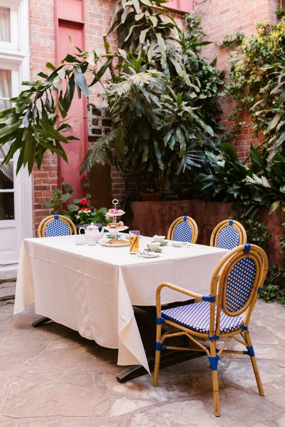 Mesa con té y dulces en un patio con sillas azules y plantas