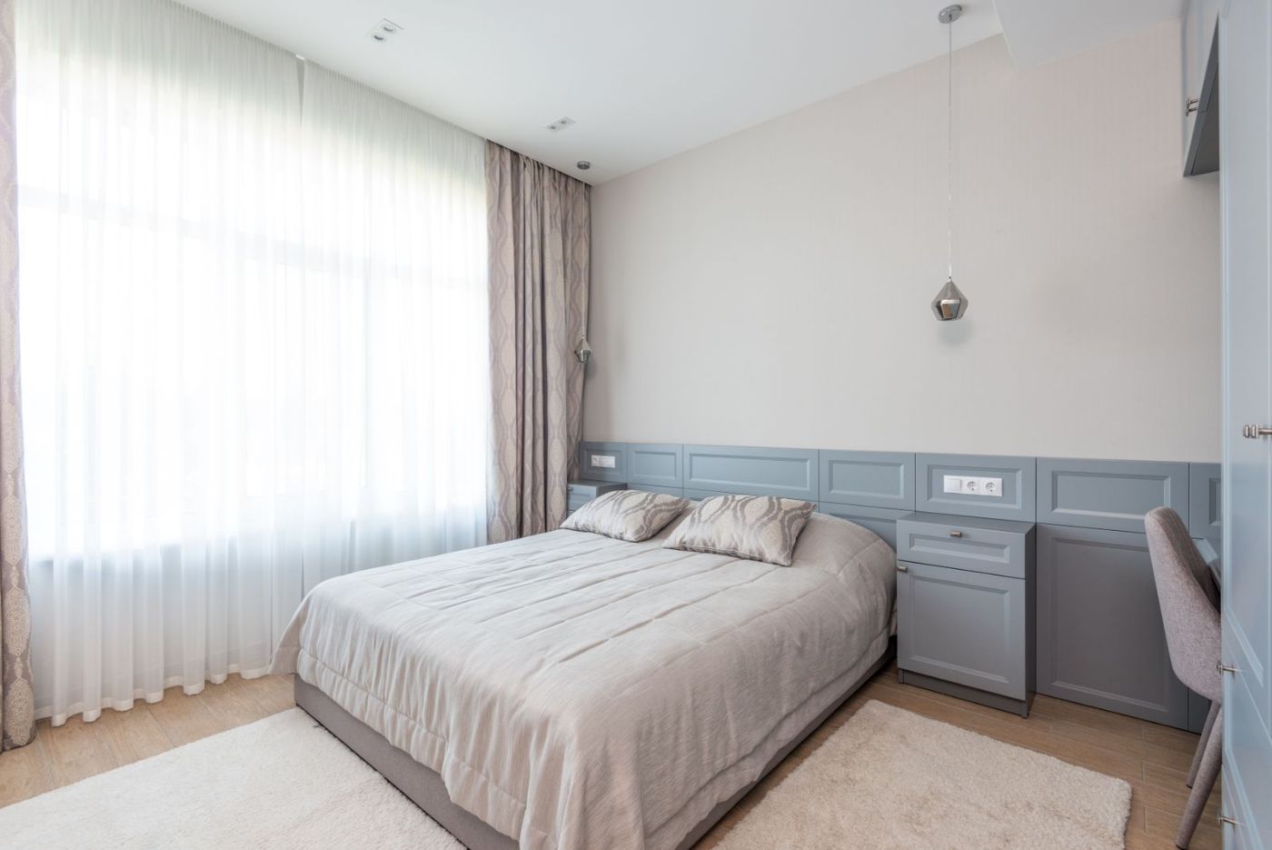 Habitación abuhardillada con cama de matrimonio y paredes gris azulado