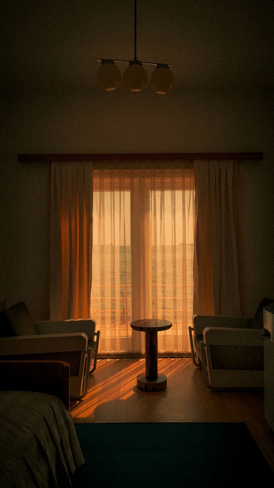 Salón con butacas de madera junto a una ventana con cortinas ámbar