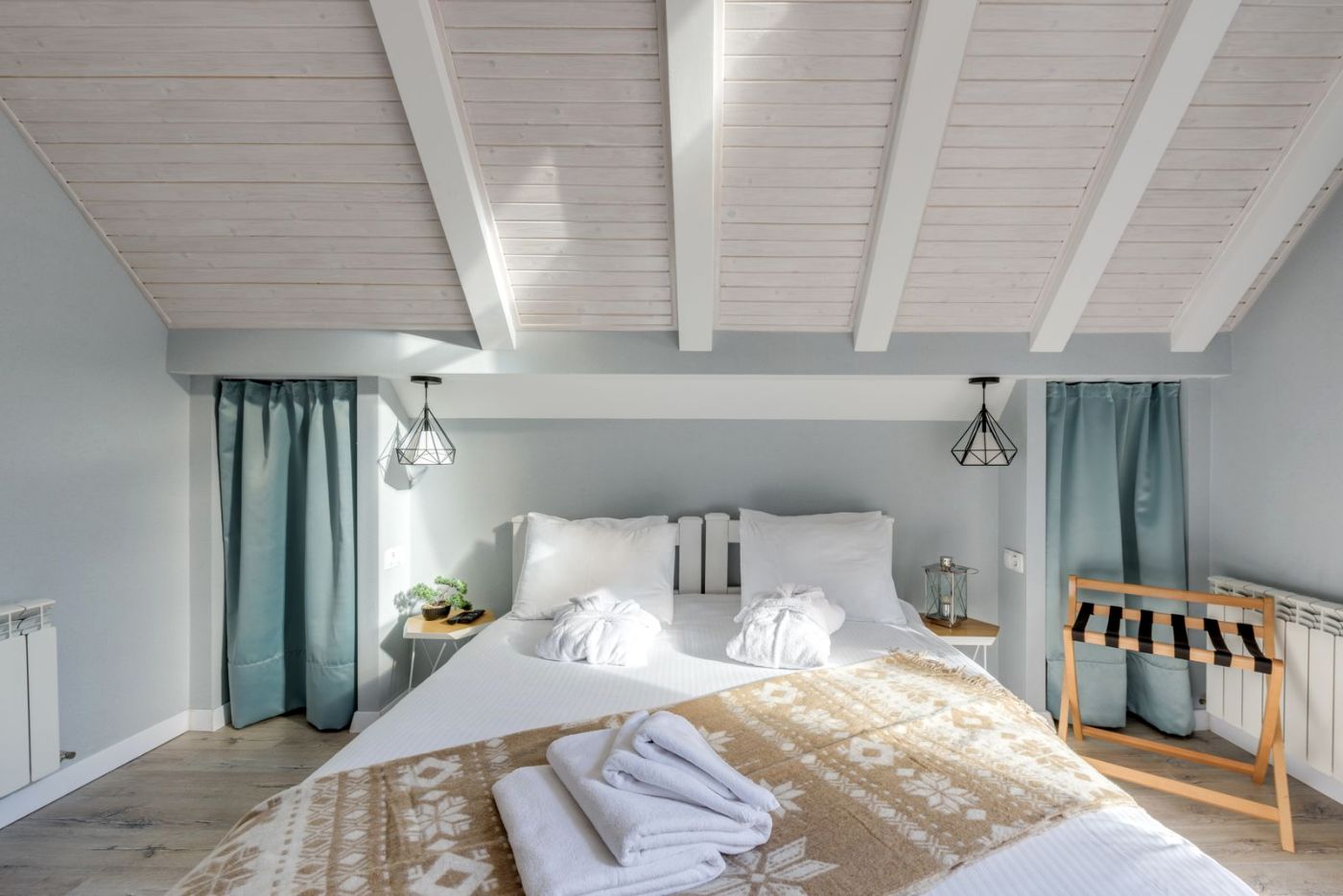 Cama doble con ropa blanca y techo claro en una habitación luminosa