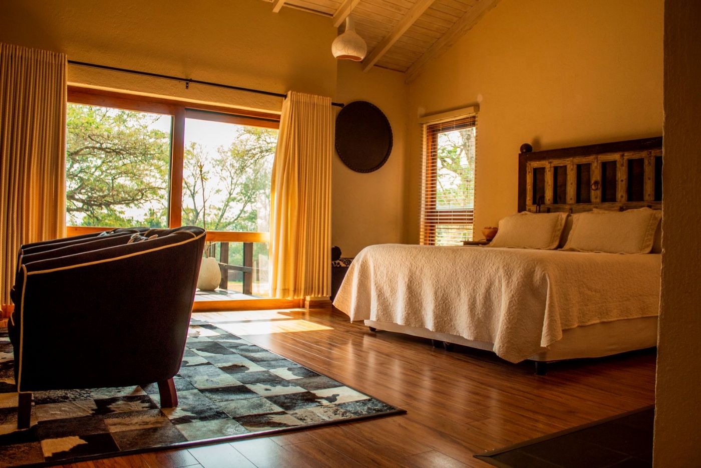 Dormitorio de madera con grandes ventanas y cama con colcha de cuadros