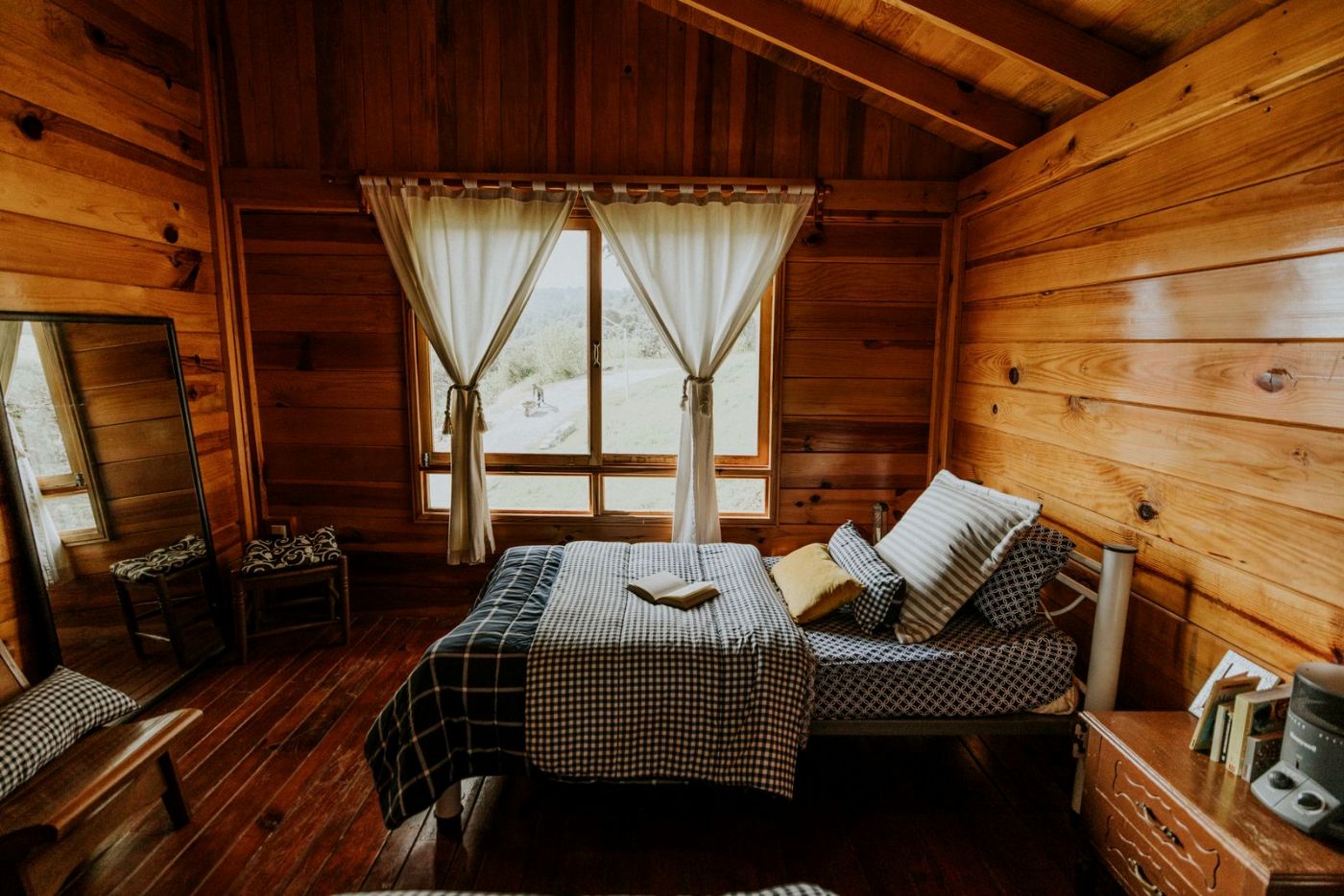 Cama junto a una ventana con vistas a la nieve y paredes de madera
