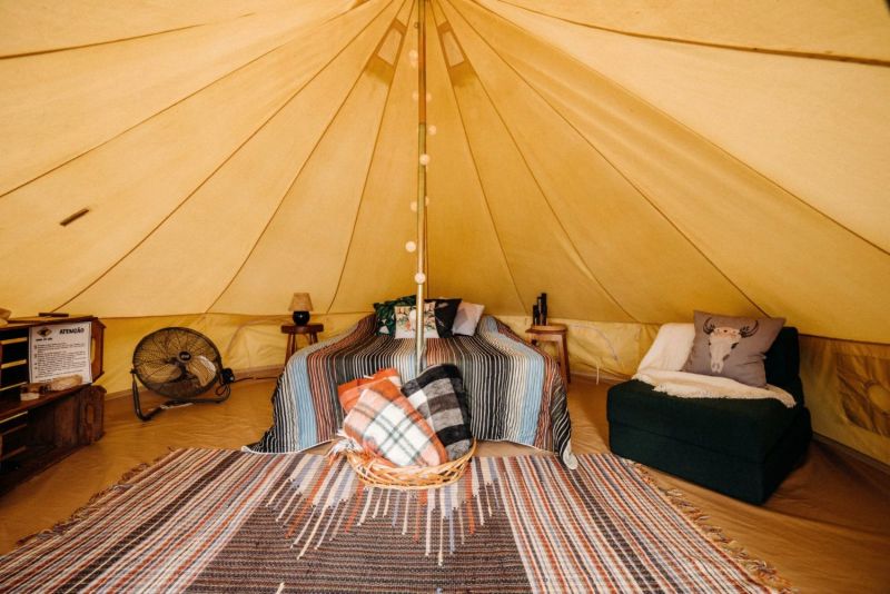 Tent interior with a bed, an armchair and a striped rug