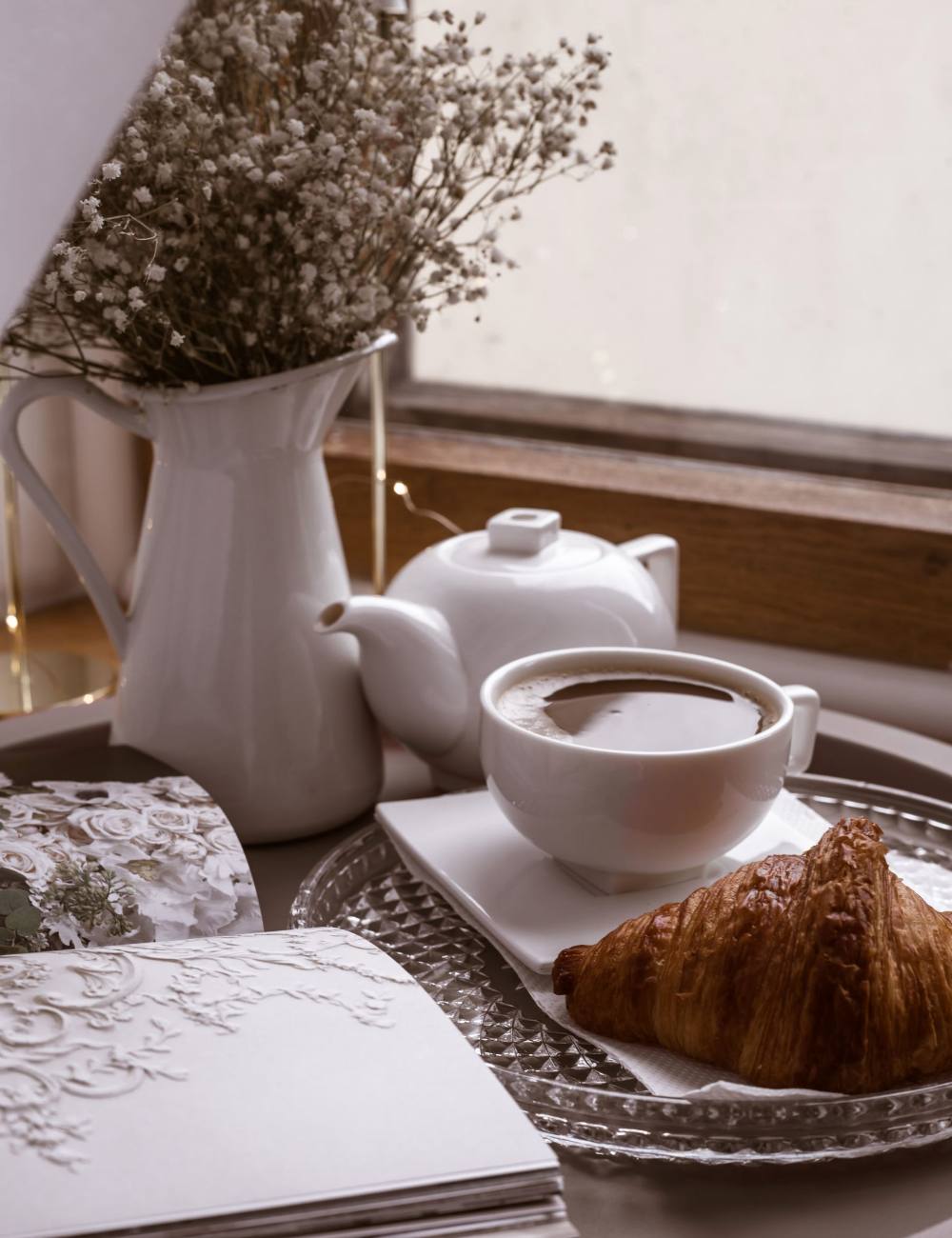 Bandeja con café, cruasán y una flor