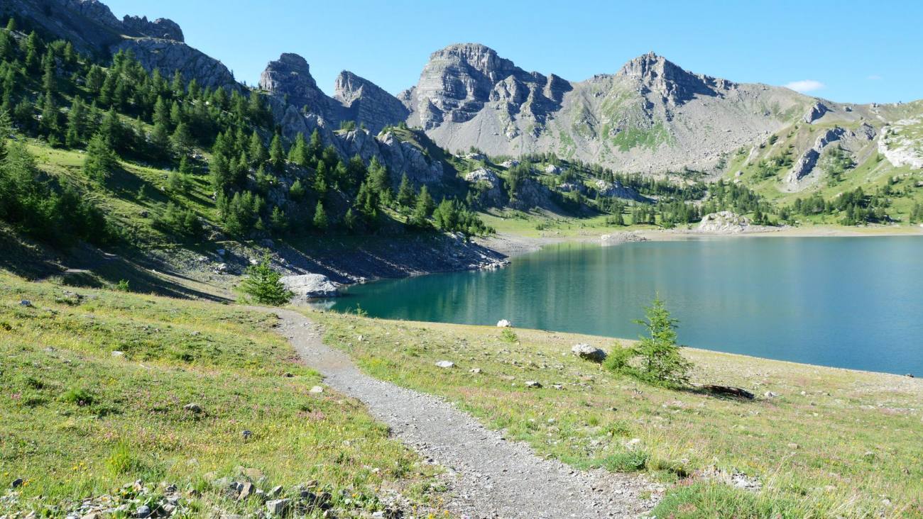 Lago de montaña con un sendero entre prados
