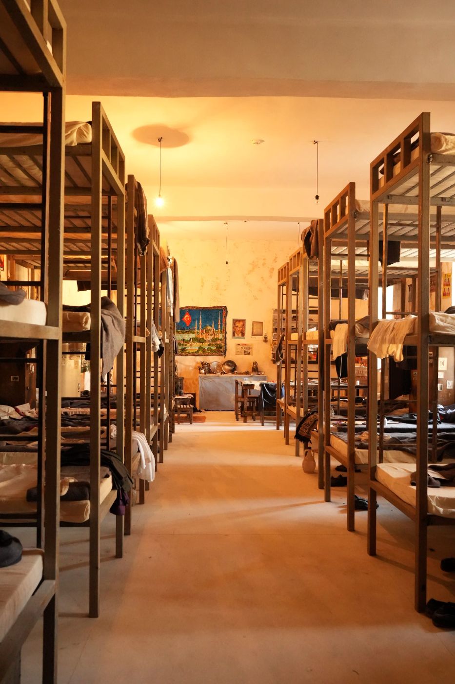 Dormitorio grande con filas de literas de madera y luz cálida