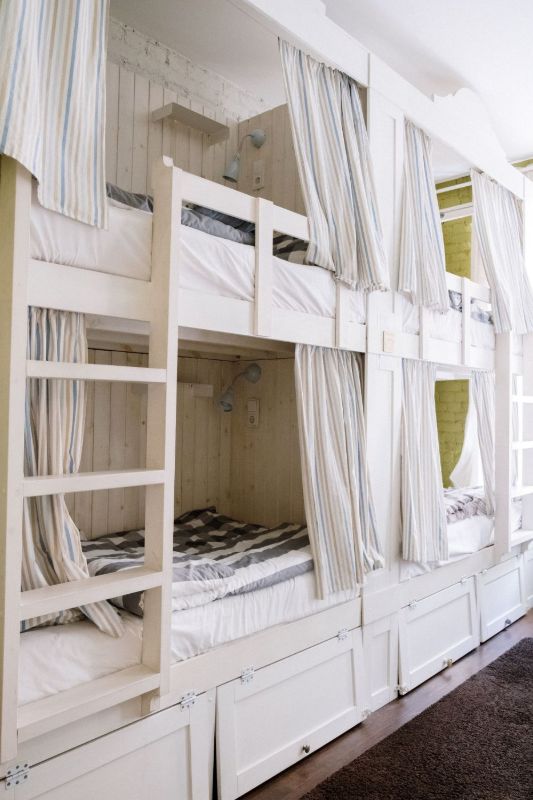 Literas blancas con cortinas de rayas y cajones debajo
