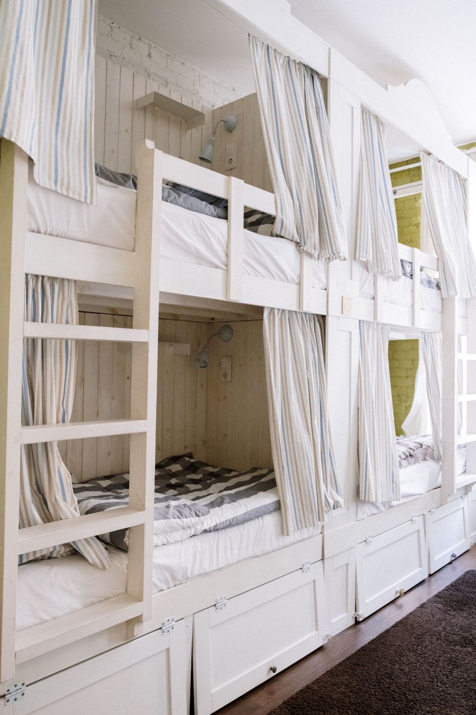 Literas blancas con cortinas de rayas y cajones debajo