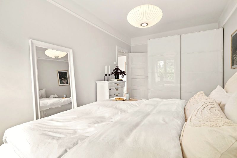Dormitorio con cama doble blanca, espejo y armario