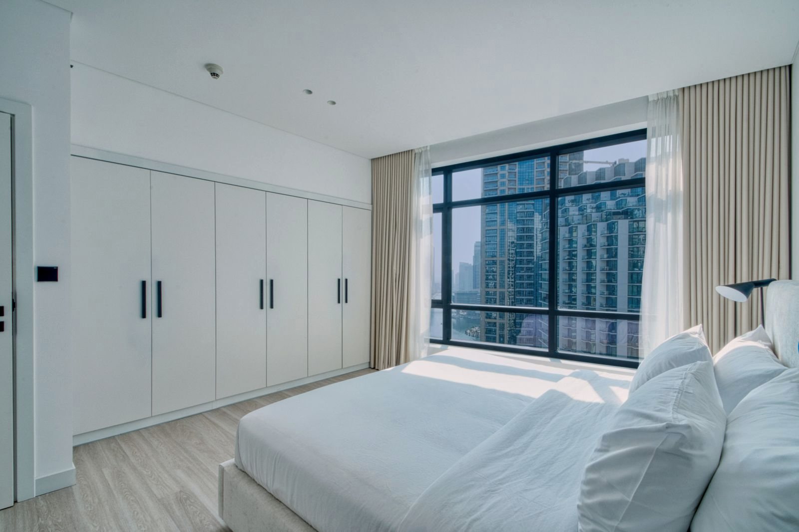 Cama doble con ventanal sobre la ciudad