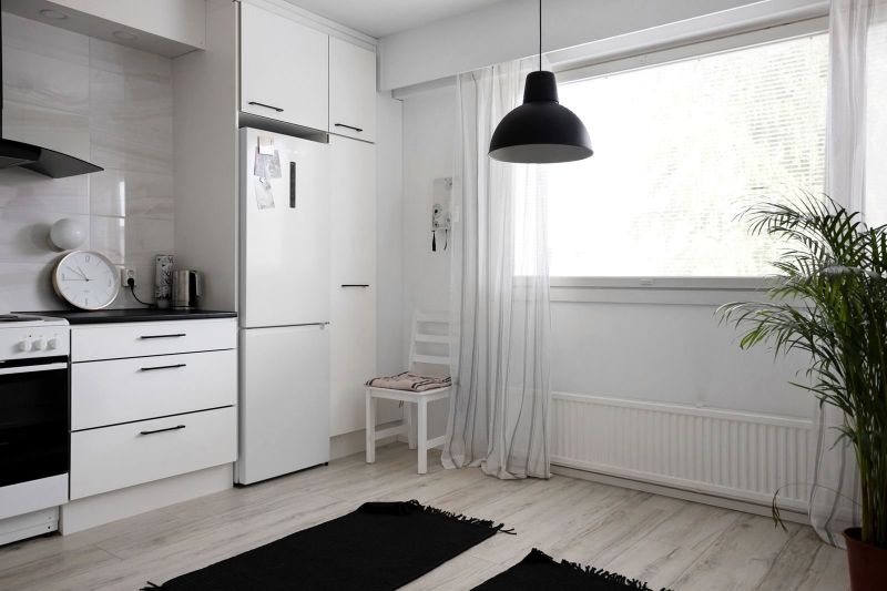 Rincón de cocina blanco con lámpara negra y ventana