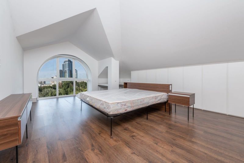Loft con suelo de madera, cama grande y ventana en arco