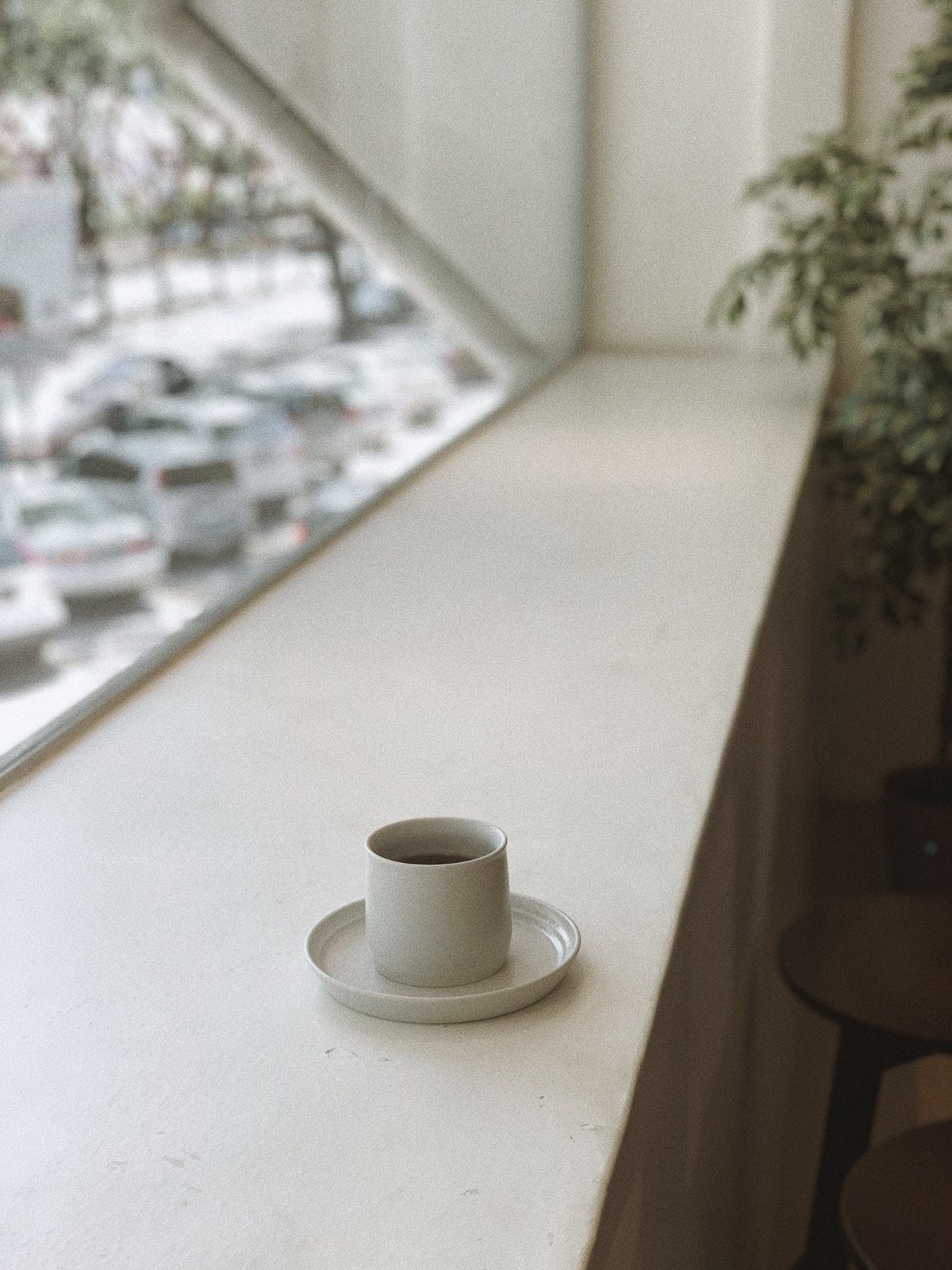 Taza de café sobre un alféizar con la ciudad desenfocada al fondo