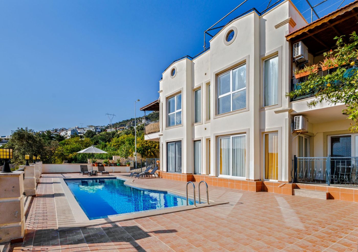 Villa blanca con piscina y terraza bajo un cielo azul