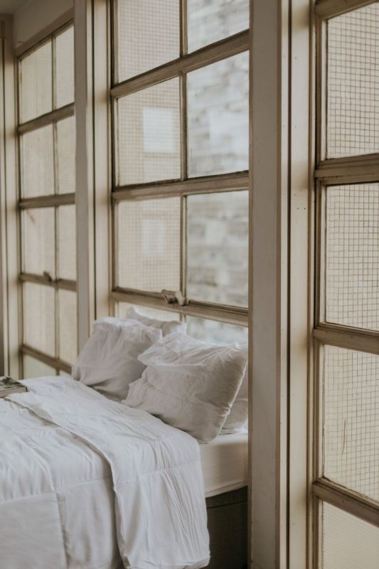 Rincón de lectura con cojines junto a ventanas con marco de madera