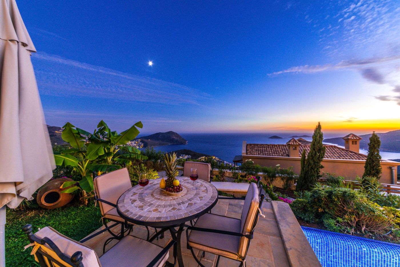 Mesa y sillas en una terraza con vistas al mar al atardecer
