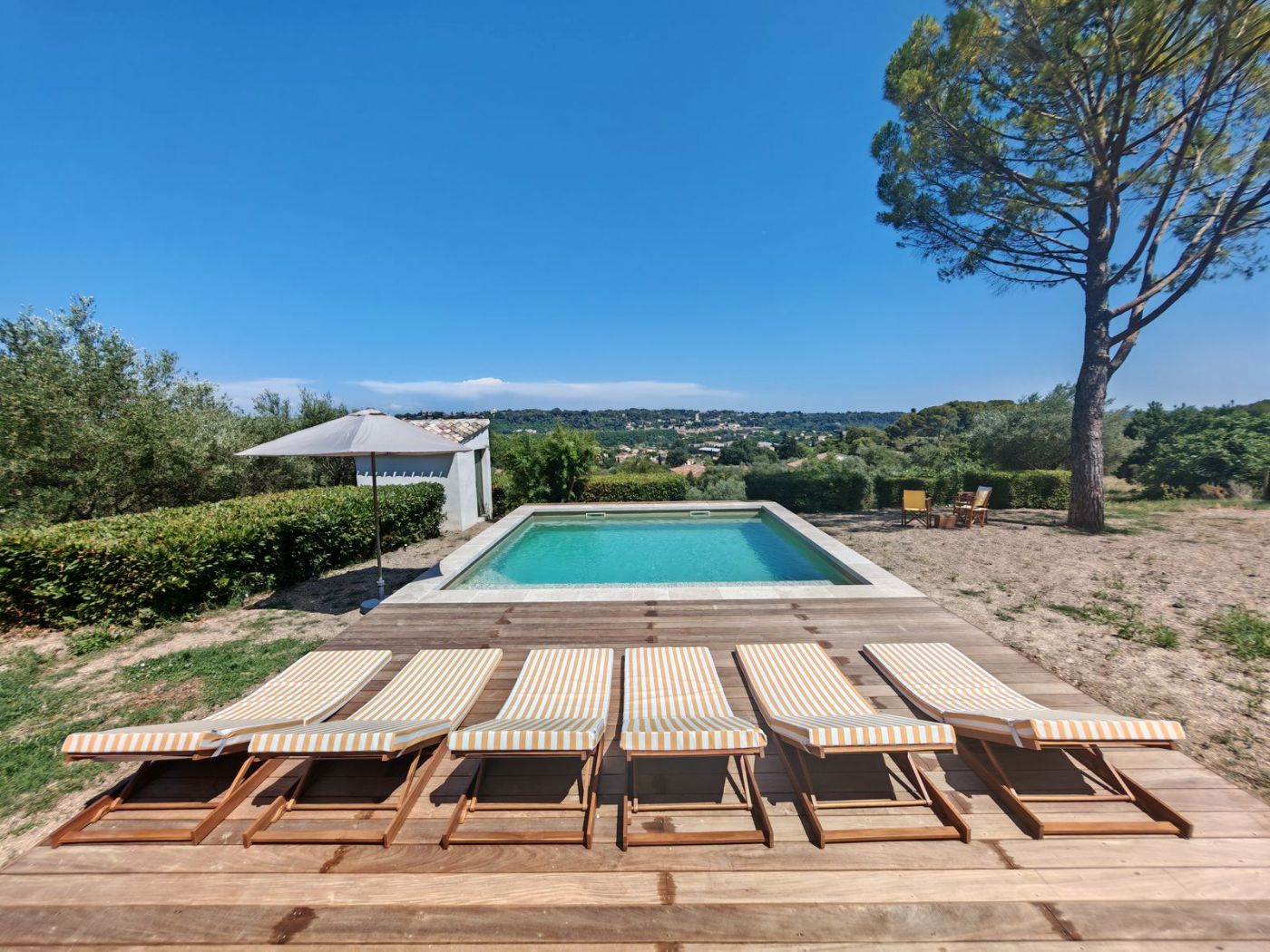 Terraza con tumbonas y sombrillas junto a la piscina y el mar
