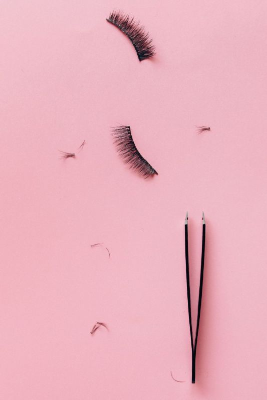 Pinzette e ciglia sciolte su fondo rosa