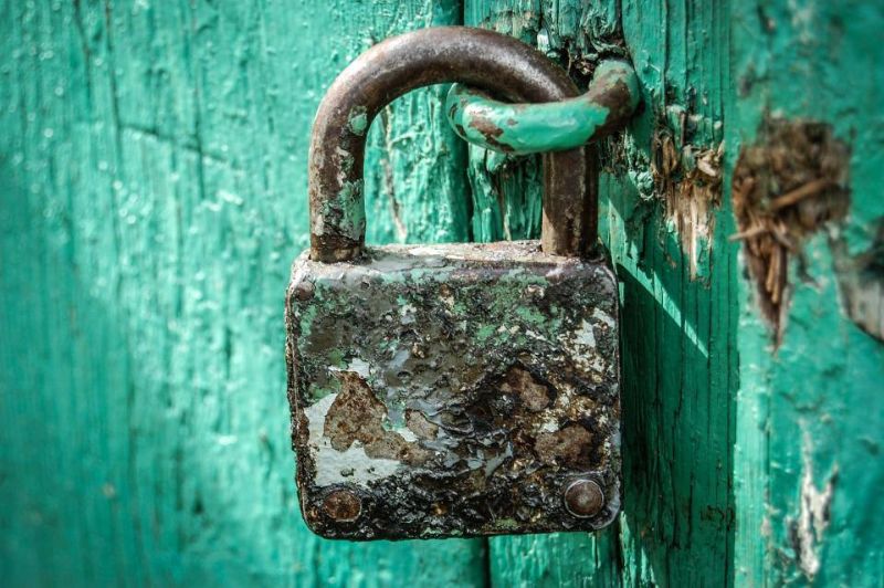 Candado verde sobre una puerta de madera pintada