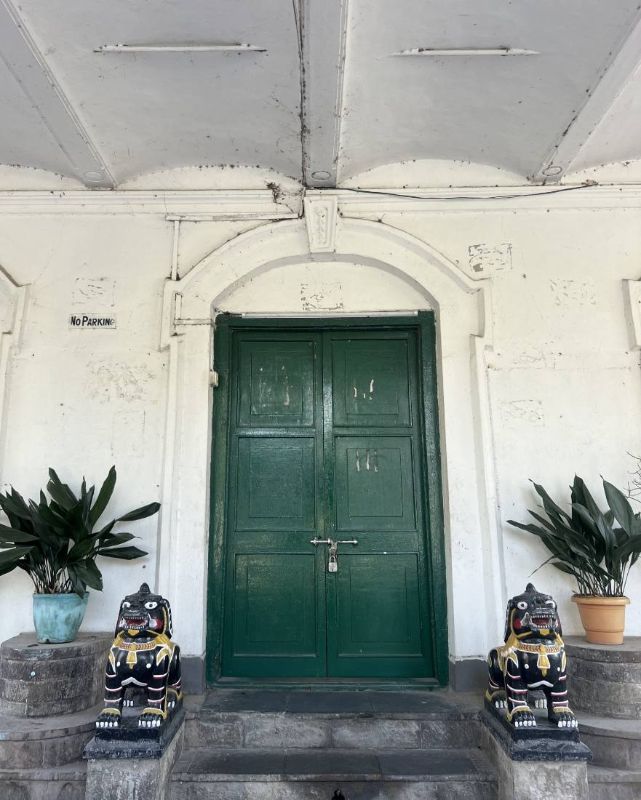Puerta verde con un candado en una fachada clara