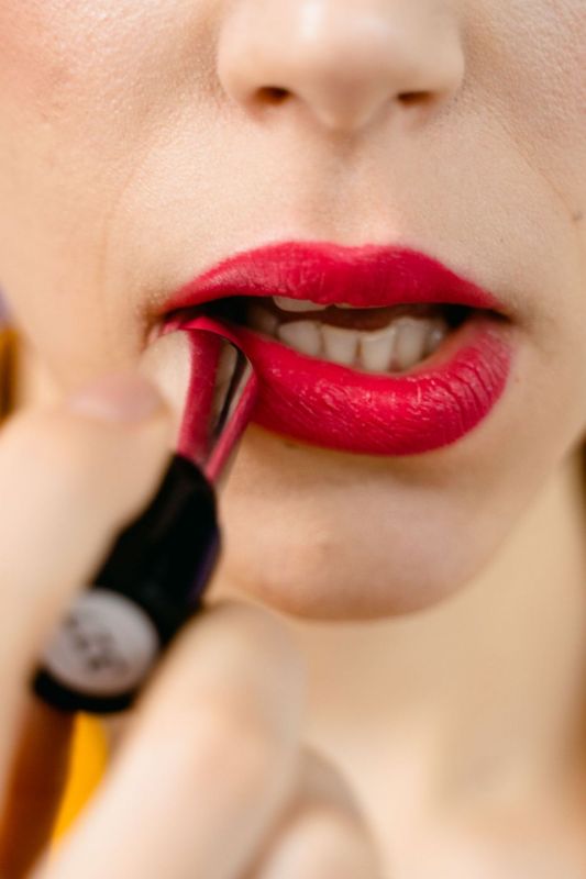 Primer plano de unos labios rojos mientras se aplica el color con un pincel