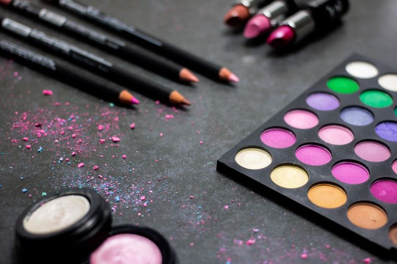 Pencils and an eyeshadow palette on a dark surface