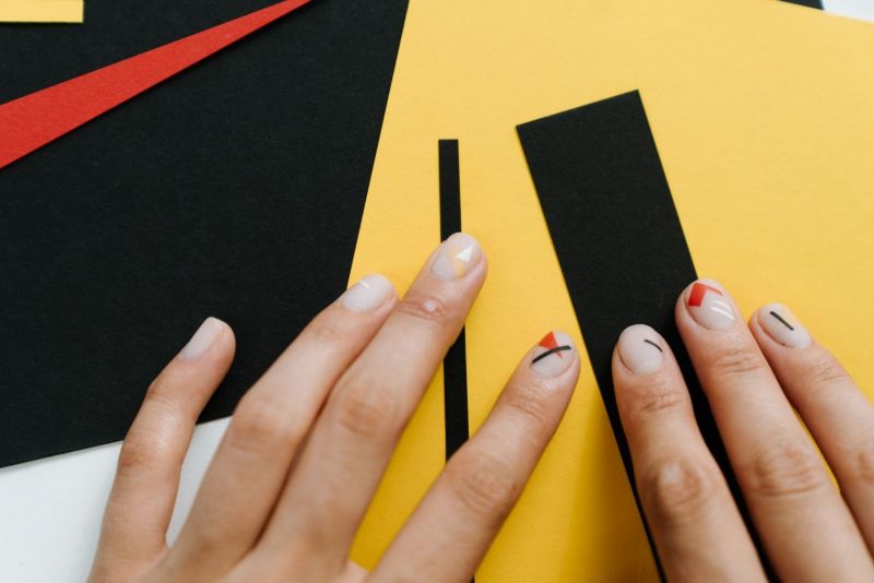 Mani con nail art geometrica su carte colorate