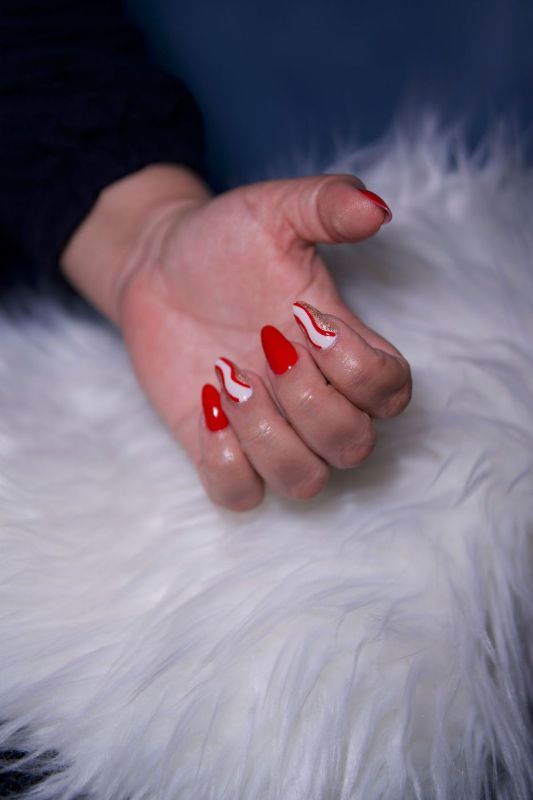 Mano con unghie rosse su una superficie bianca e soffice