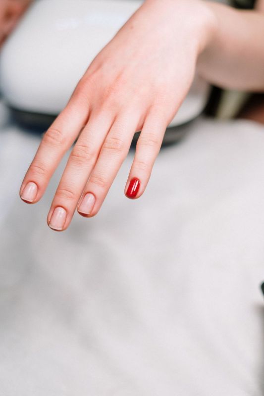 Manicure rossa minimal su tessuto bianco