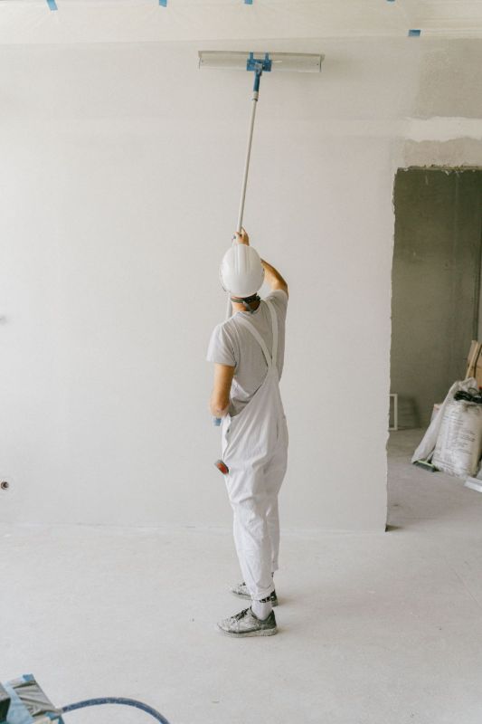 Pintor con mono blanco pintando una pared desde atrás