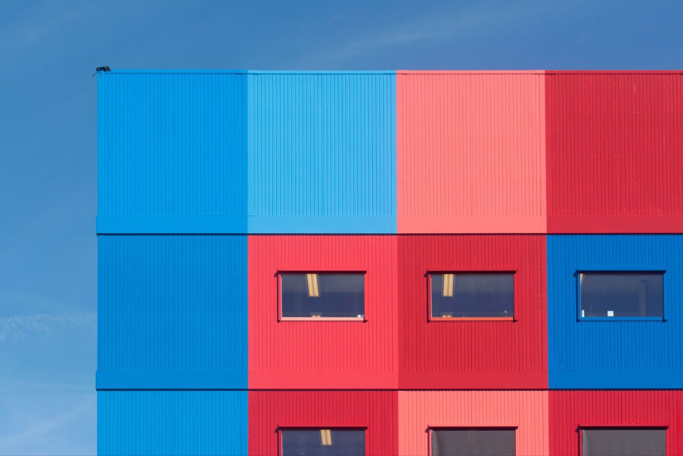 Façade d’immeuble bleue et rouge sous un ciel clair