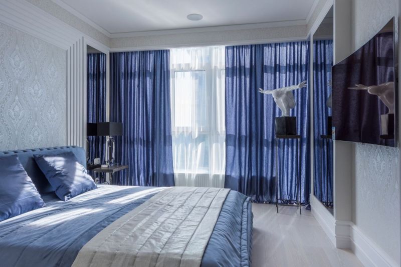 Chambre bleue avec longs rideaux et grande baie