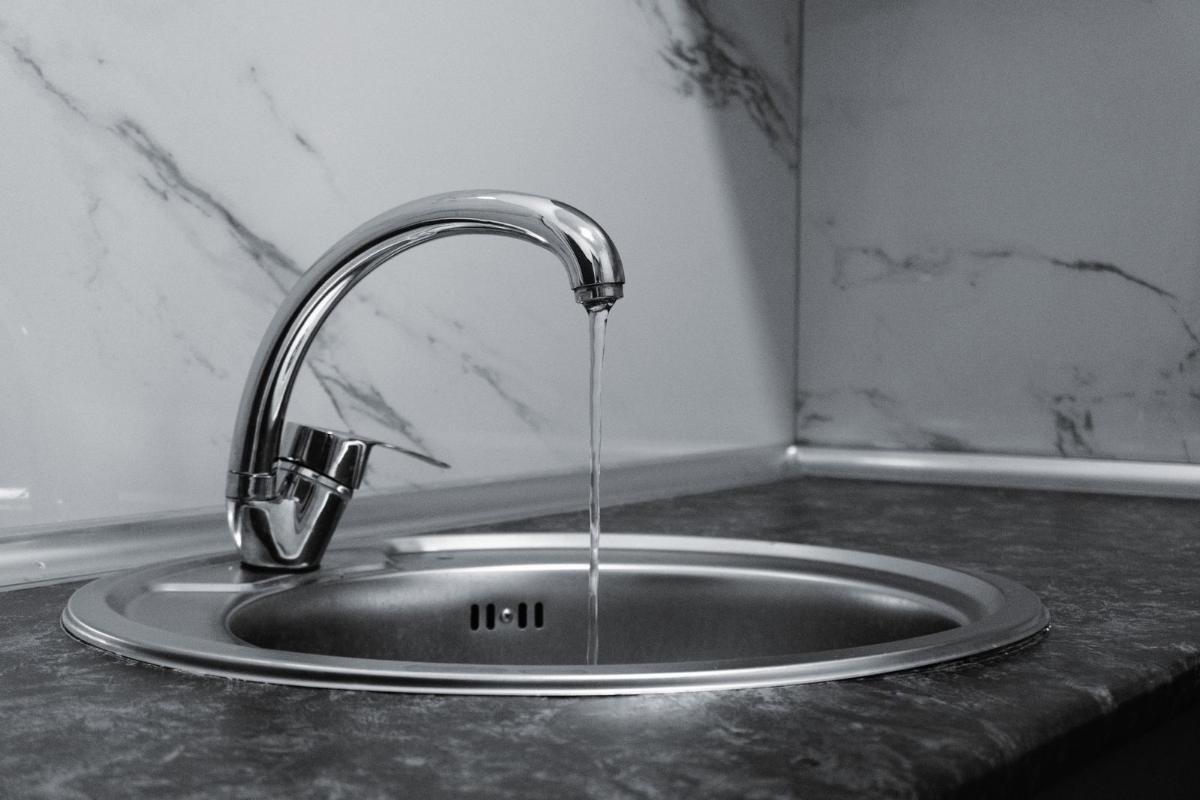 Grifo cromado con agua sobre encimera de mármol