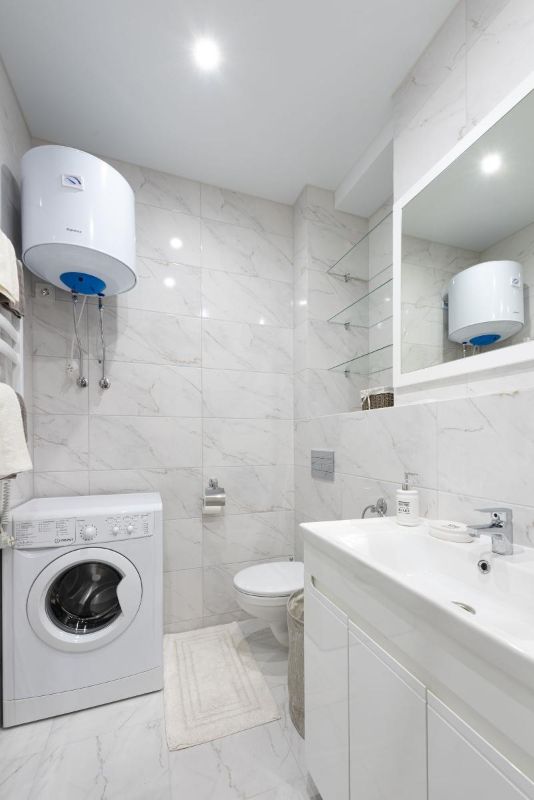 Baño blanco con un calentador de agua en la pared