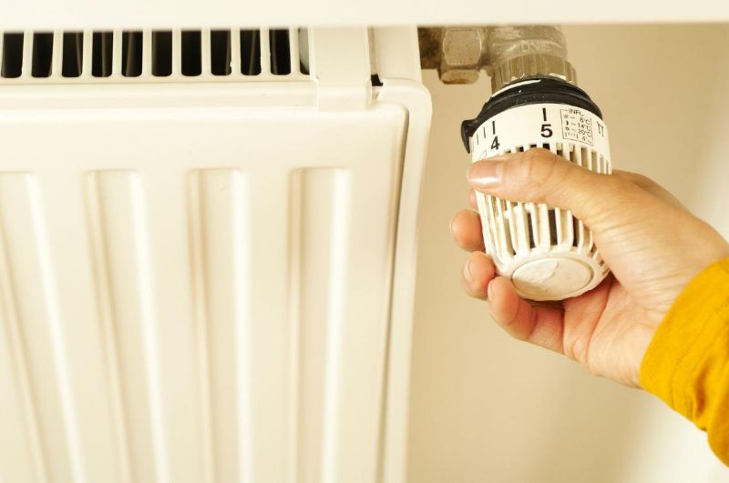 Mano girando la válvula de un radiador